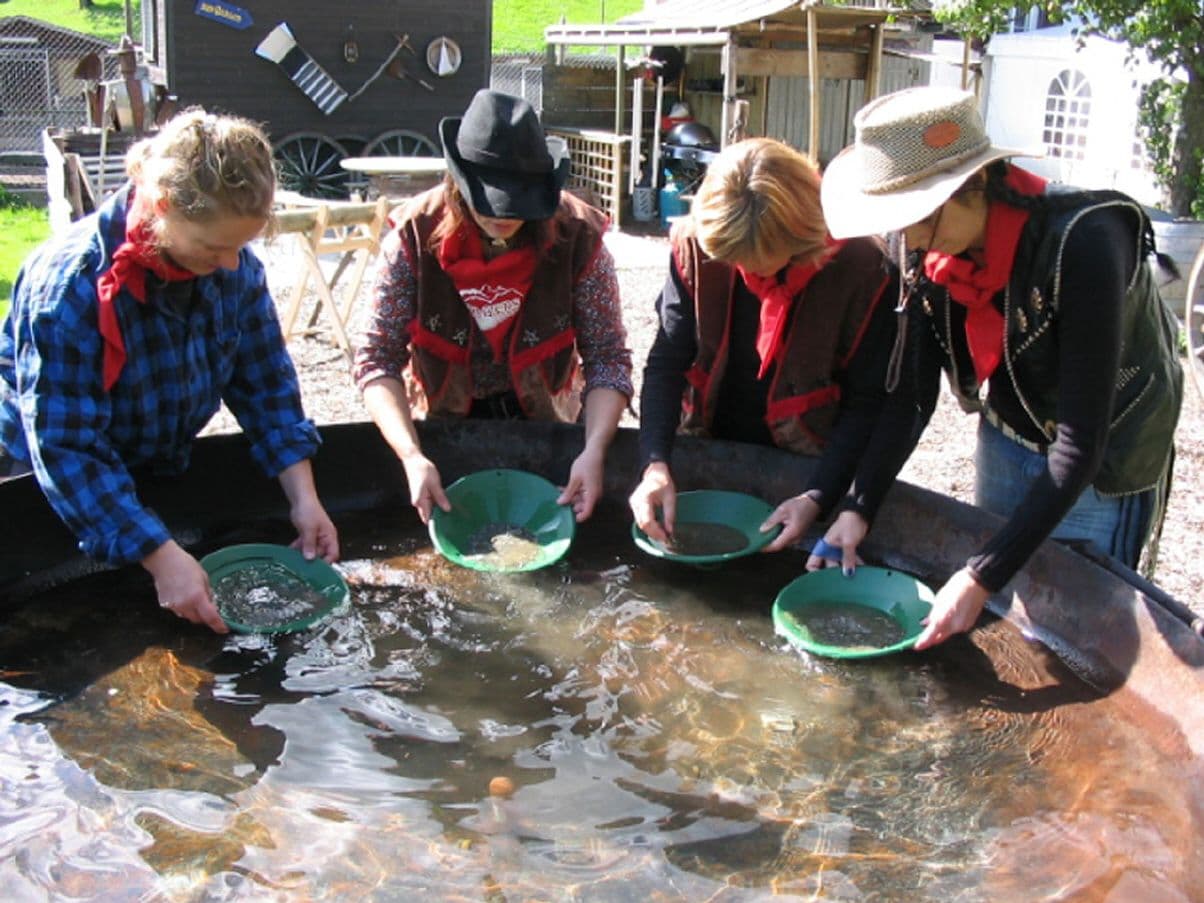 Gold prospecting during the Western Olympics 2023 with participants, water buckets, and gold pans.