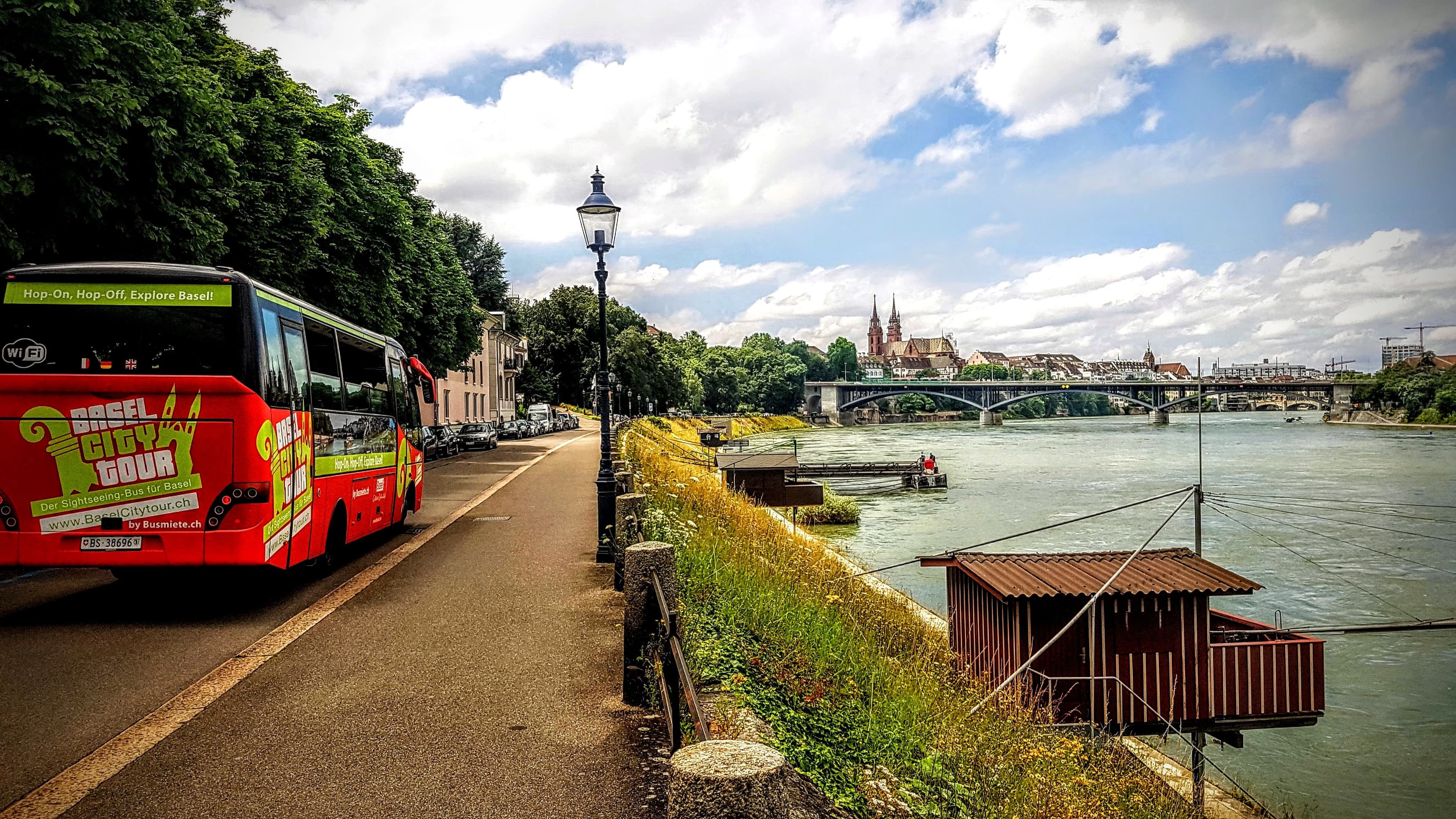 Basel bus tour sightseeing trip by bus along the Rhine. Historical buildings and bridge visible.