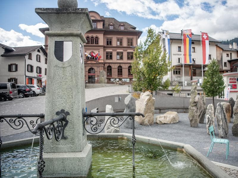 Plazza Cumin: Fountain with historic building in Ilanz, attraction, city tour, Surselva.
