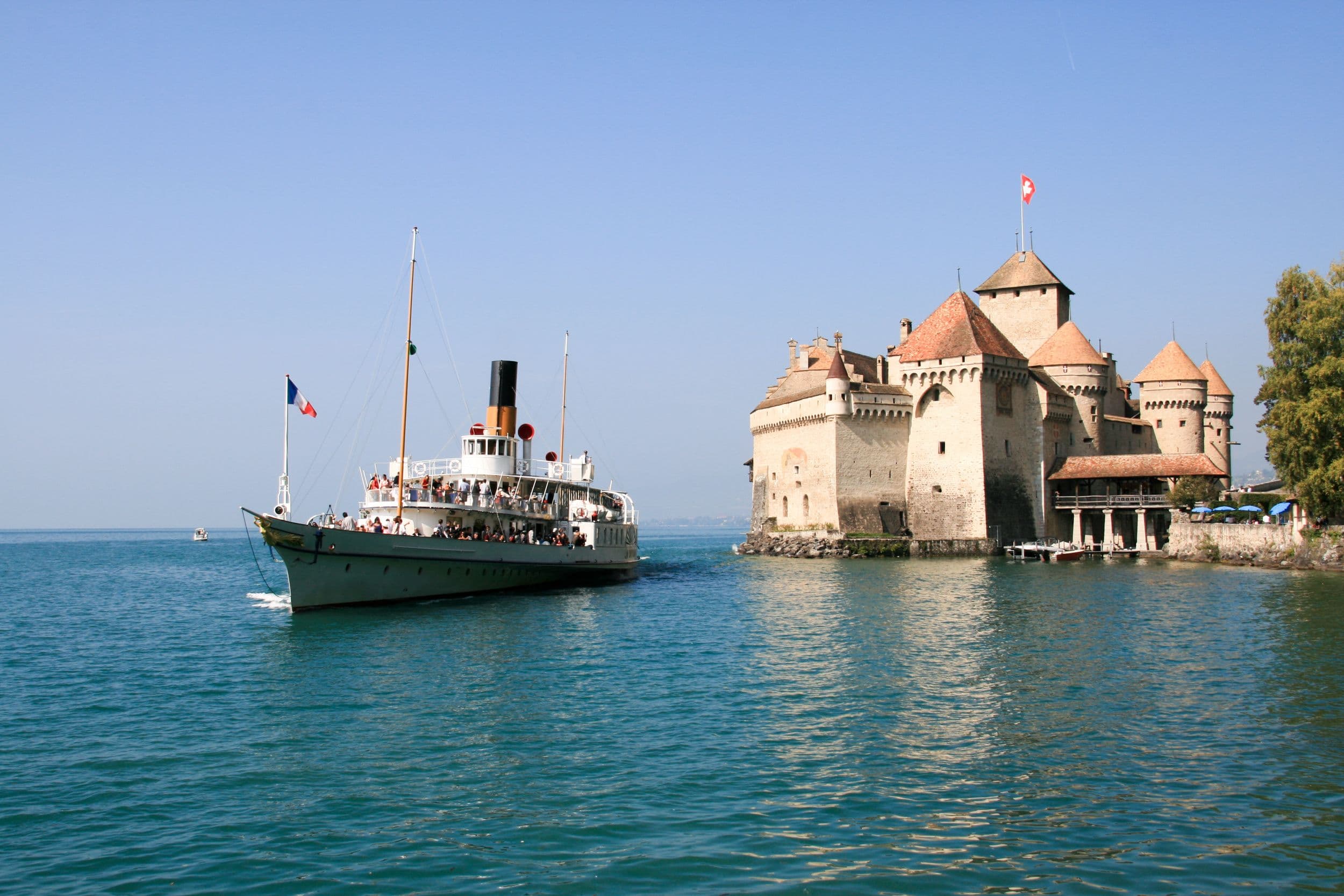 Chillon Castle, boat on Lake Geneva, clear sky, summer.