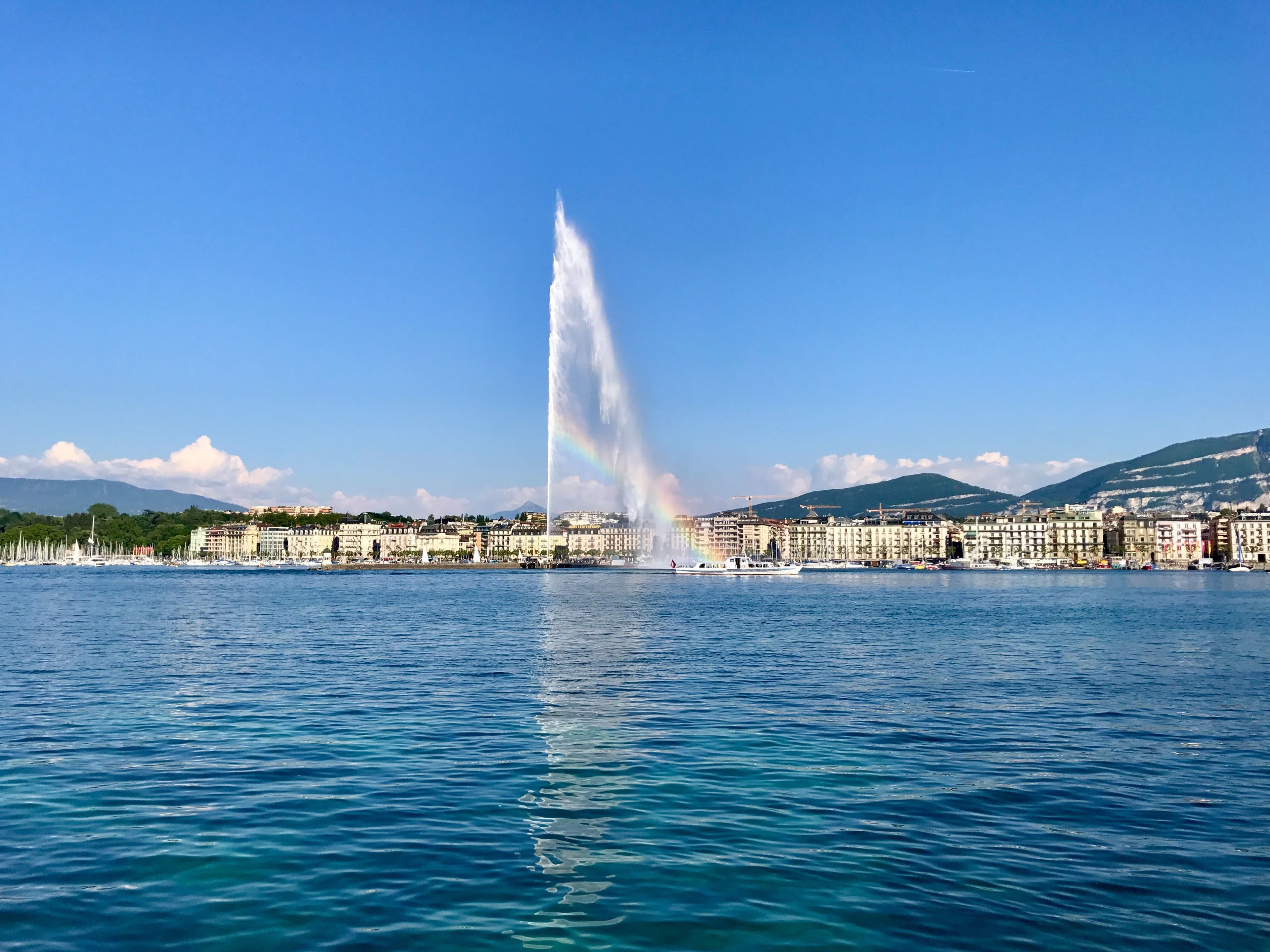 Jet d'Eau in Geneva bubbles high above the water in clear sky