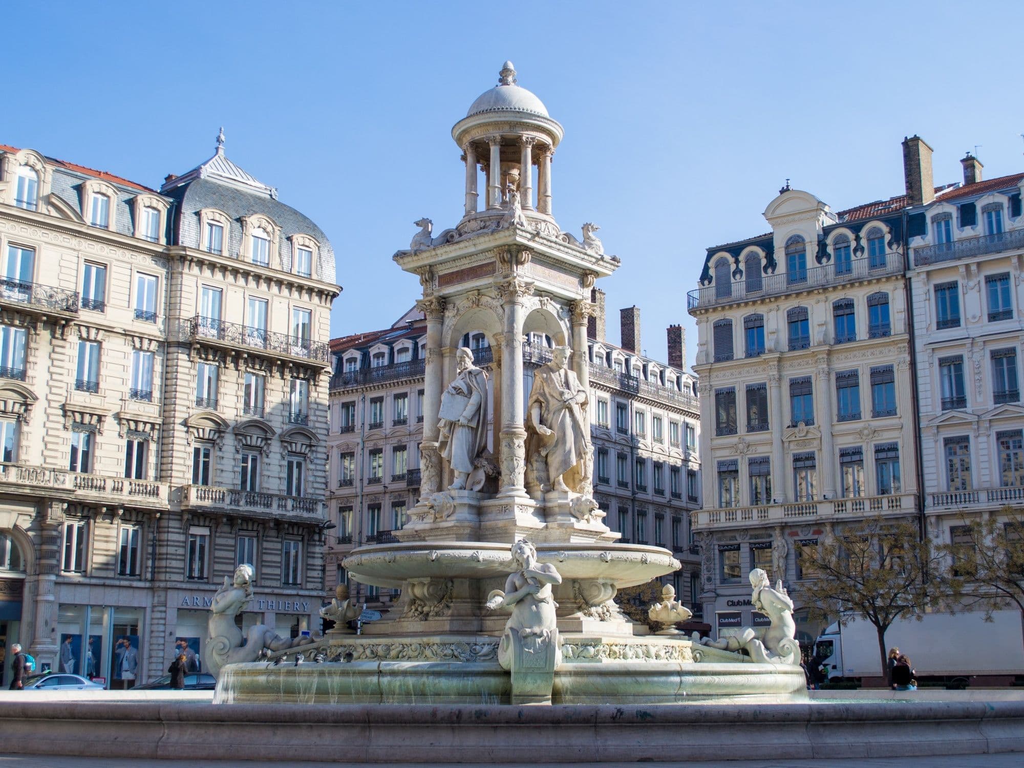 Fountain in Lyon with detailed sculptures, sunny day.