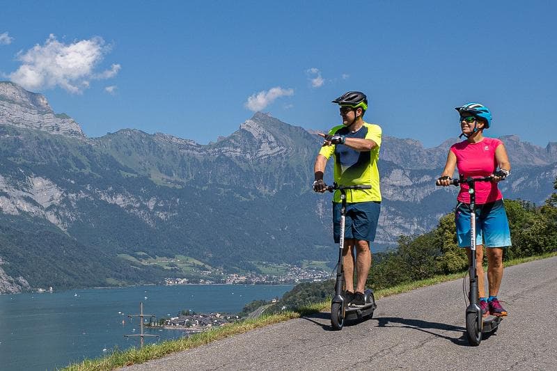 Electric scooter riders in Switzerland roll along the mountains.