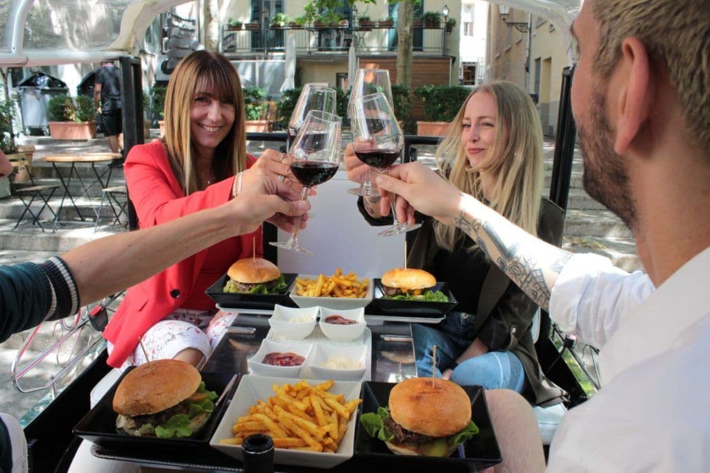 Two women toast over burgers and wine at an outdoor table.