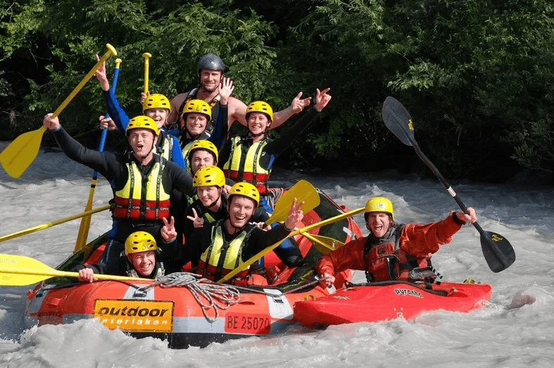 Rafting Interlaken with a cheerful team in yellow helmets, paddling in the middle of the river.